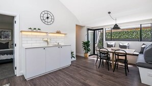 Une cuisine moderne avec des meubles blancs, une horloge et un coin repas comprenant une table et des chaises.