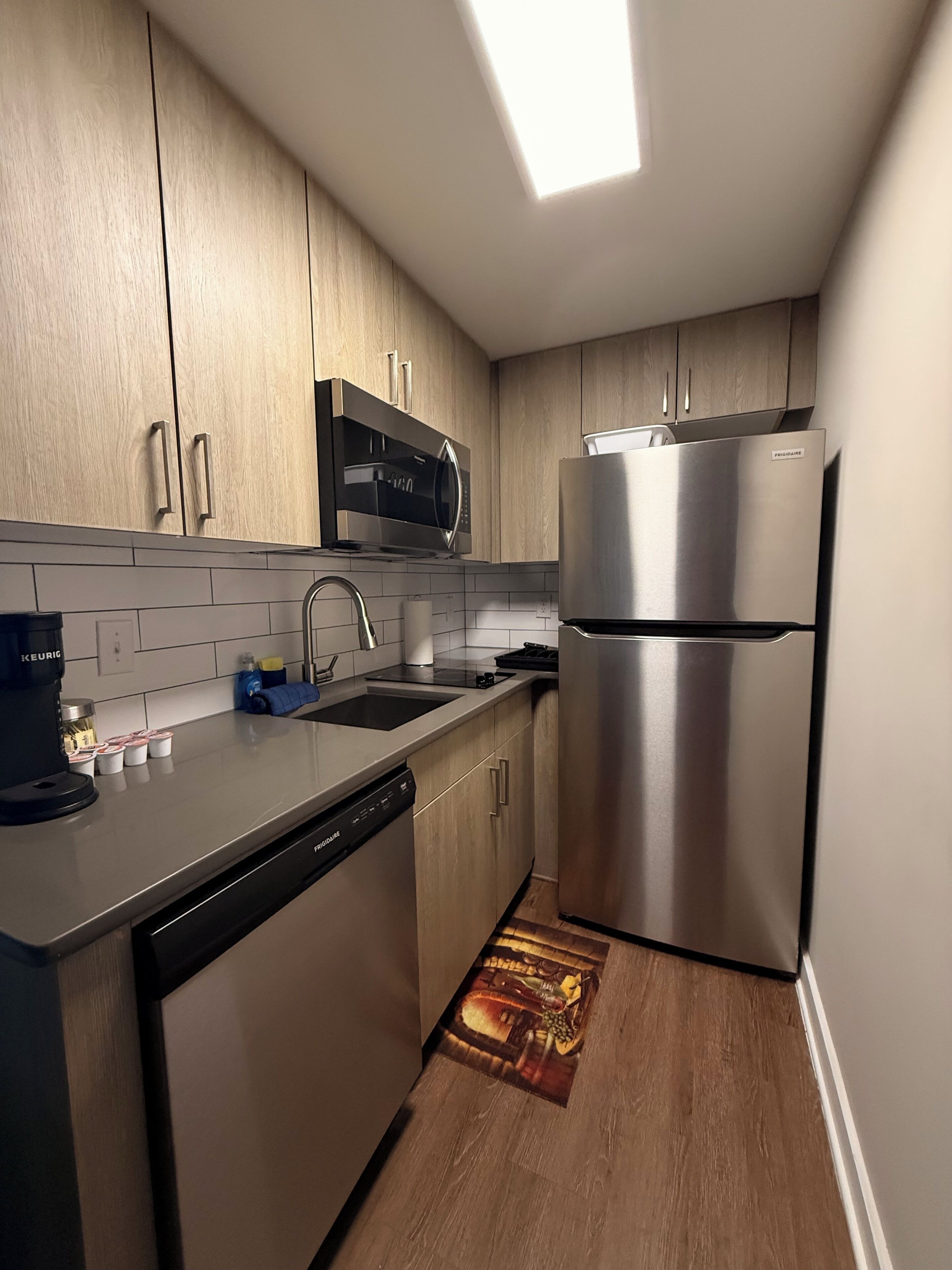 A modern kitchen with stainless steel appliances, wooden cabinets, and a dishwasher.