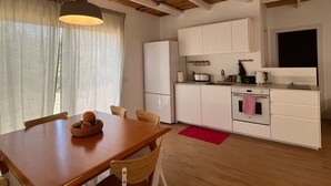 A kitchen with white cabinets, a wooden table with chairs, a red rug, and a window with curtains. - Large Guesthouse 80m in lovely Ramot (Ramot)