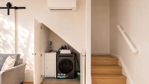Une buanderie équipée d’un lave-linge, d’un étendoir et d’un petit évier.