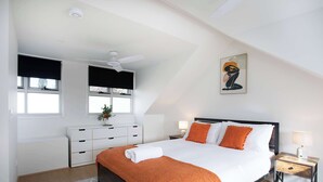 Une chambre à coucher avec un lit, une table de chevet, une commode et un tableau au mur.
