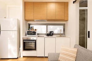 A compact kitchen with a refrigerator, microwave, oven, and a coffee maker. - The Loft | Charming 1BR Glebe, Near Sydney Uni (Glebe)