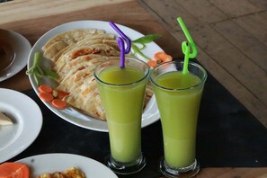 Uma mesa com um prato de pães achatados e dois copos de suco verde.