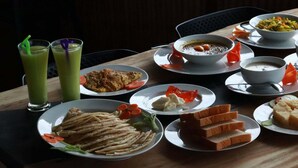 Una mesa de comedor con varios platos, entre ellos sopa, pan y ensalada.