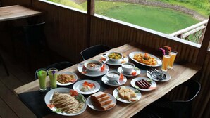 Una mesa de comedor con diversos platos, vasos de bebidas y cubiertos.