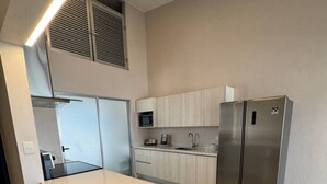 Eine moderne Küche mit einer zentralen Kochinsel, Barhocker, einer Mikrowelle, einem Spülbecken und einem Edelstahl-Kühlschrank.