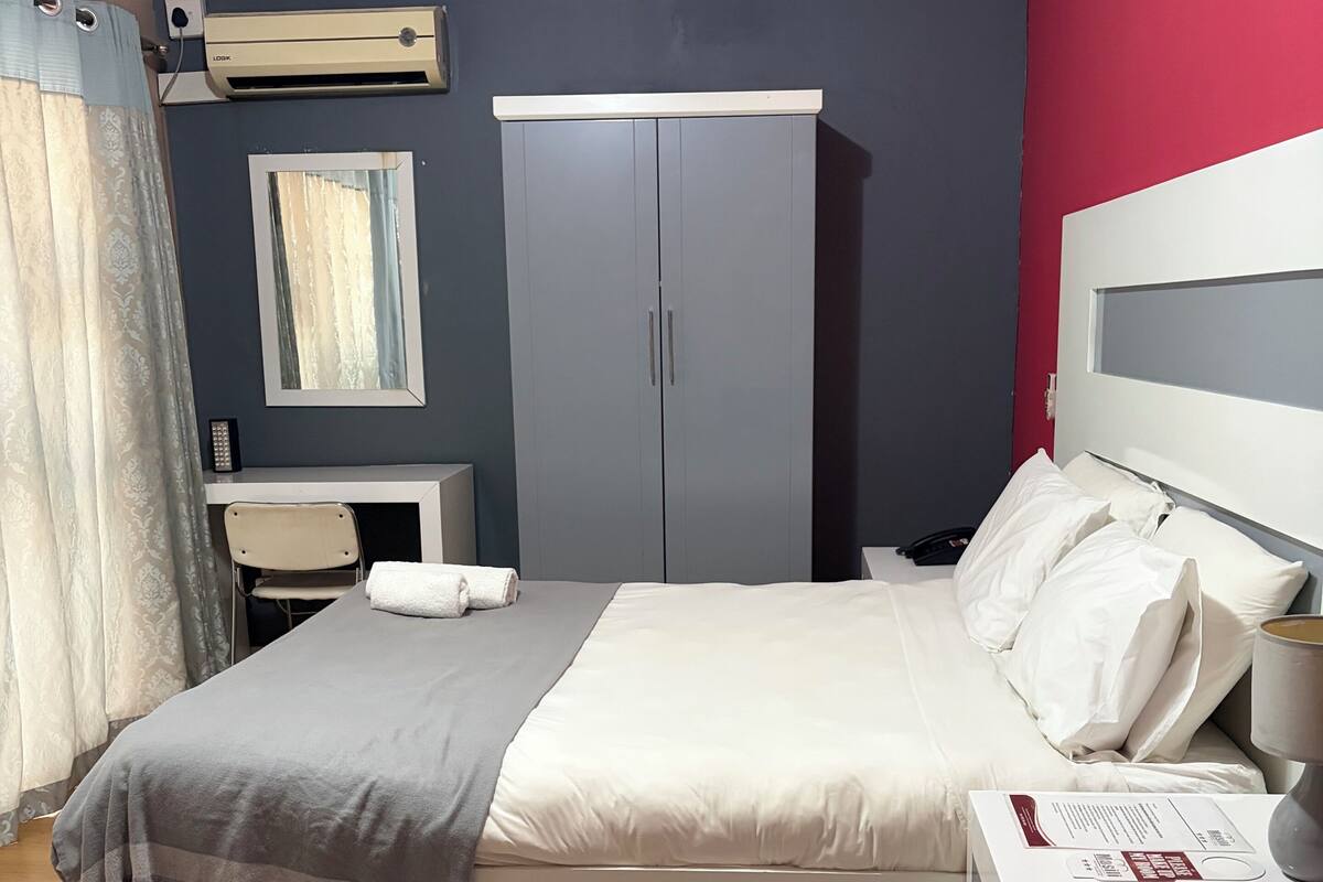 A bedroom with a bed, bedside table, lamp, and a wardrobe.
