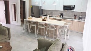 Ein modernes Wohnzimmer mit einer Couch, einem Essbereich mit Stühlen und einer Küche mit Schränken und Geräten.