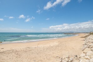 Ein Strand mit felsigem Ufer, ruhiger See und blauem Himmel.