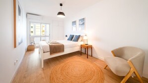 A modern bedroom with a bed, bedside table, chair, and artwork. - GuestReady - Stay at Costa da Caparica (Costa de Caparica)