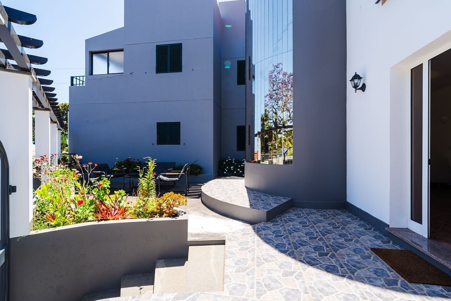 Ein modernes Gebäude mit einer geschwungenen Treppe, Außenplätzen und einer terrasse mit Steinputz.
