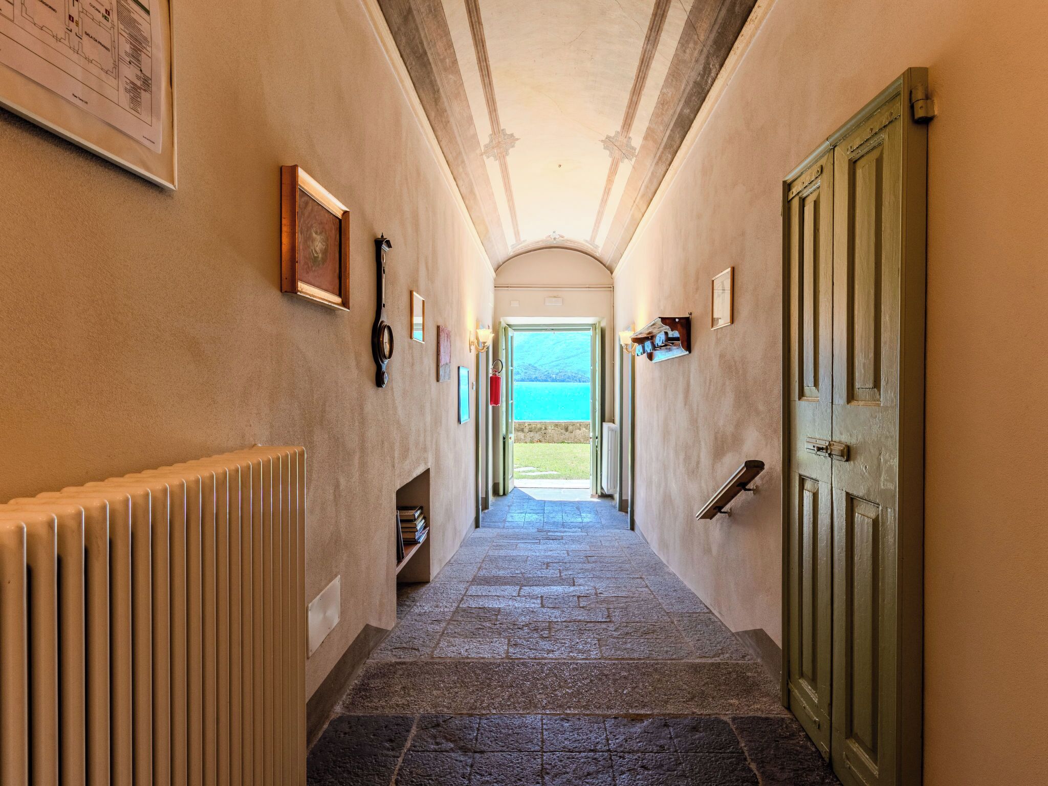 A hallway with stone flooring, a radiator, a door, and a view of the sea.