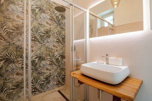 A bathroom with a shower, a sink with a wooden countertop, and a floral-patterned wall. - A wonderful home in the historic district (Castellana Grotte)