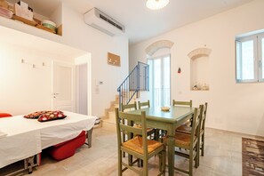 A dining area with a table and chairs, a staircase, and a window with a view. - A wonderful home in the historic district (Castellana Grotte)