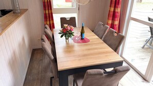 Ein Essbereich mit Holztisch, Stühlen, einer Blumenvase und einer Weinflasche.