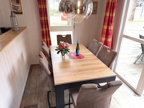 Ein Essbereich mit Holztisch, Stühlen, einer Blumenvase und einer Weinflasche.