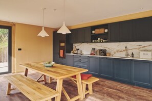 Een moderne keuken met donkere kasten, een marmeren spatwand en houten meubels.