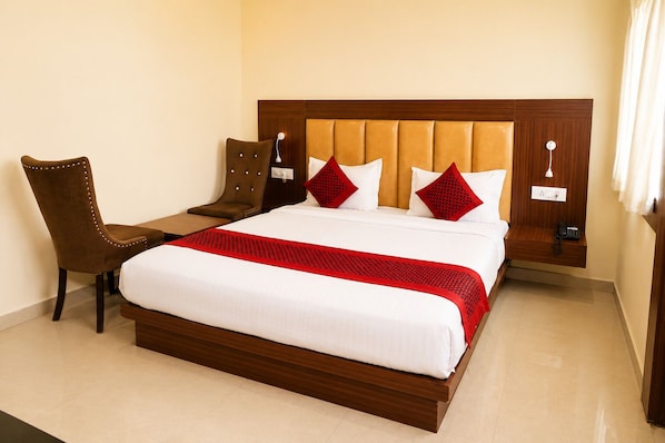 A hotel room with a large bed, a chair, a bedside table, and a phone. - Hotel the venus (Rudrapur)