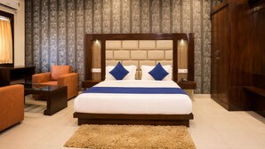 Una habitación de hotel con una cama grande, un sofá, un televisor y un armario.
