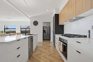 Eine moderne Küche mit weißen Schränken, einem Edelstahlkühlschrank, einem Gasherd und einem Geschirrspüler.