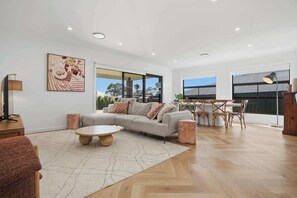 Uma sala de estar ampla com sofá, mesa de centro e conjunto de jantar.