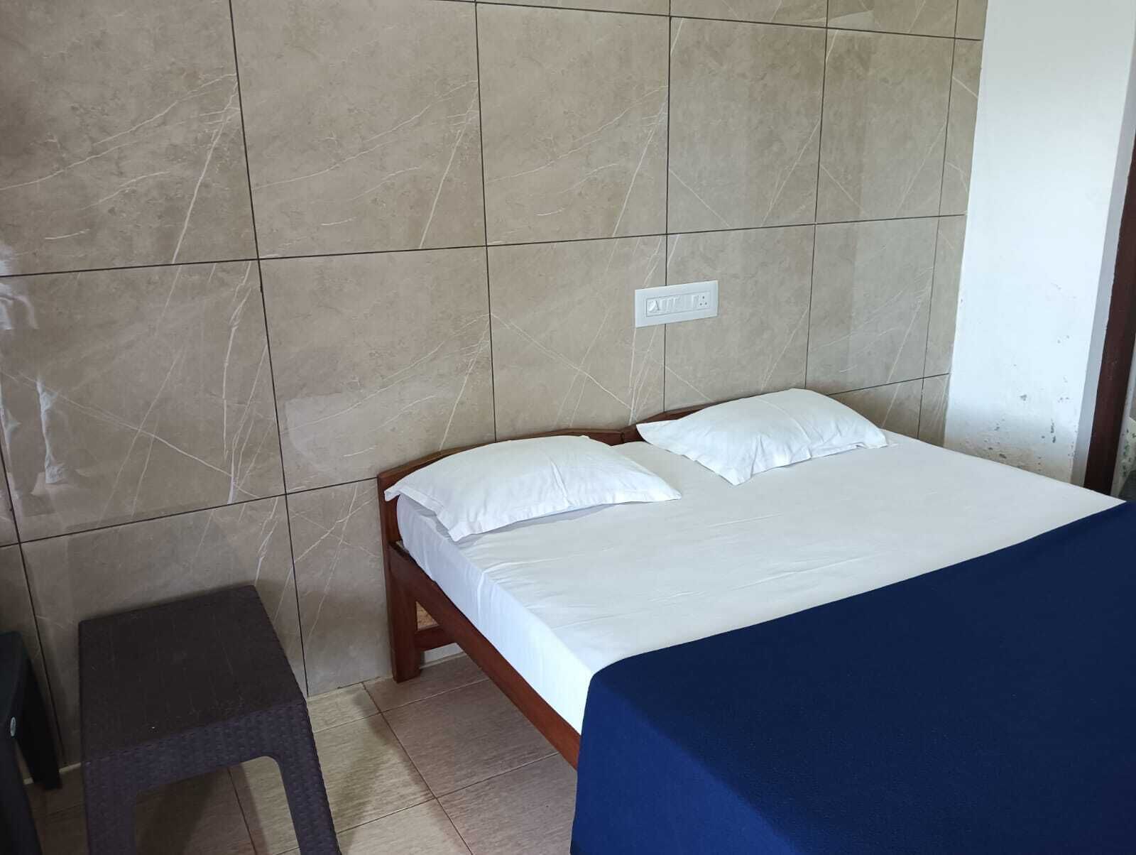 Una cama individual con ropa de cama blanca en una habitación con paredes de baldosas.