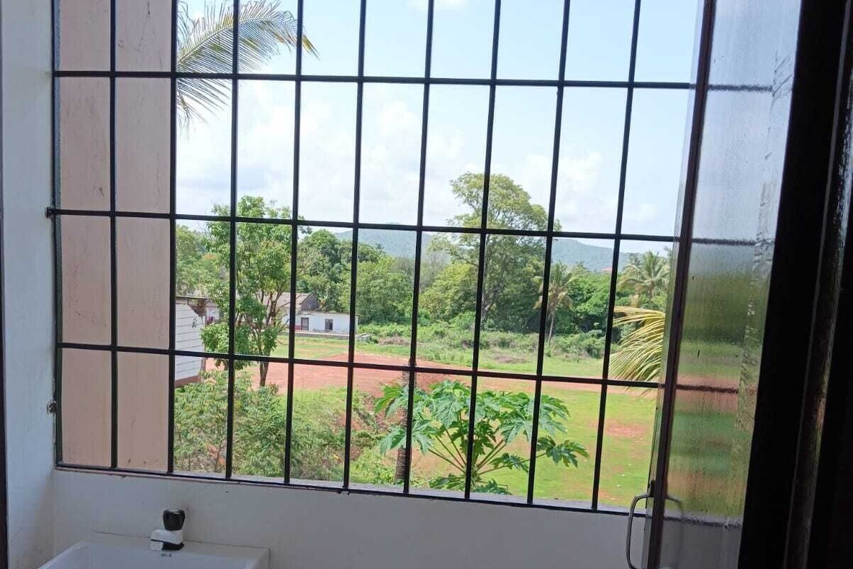 A small bathroom with a window, a sink, and a view of a green landscape.