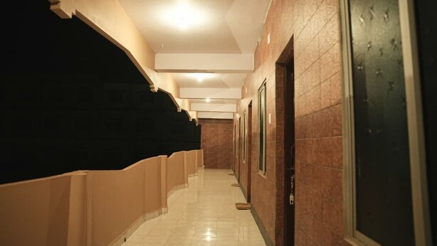 A hallway with a tiled floor, a ceiling with recessed lighting, and a door on the right. - Stone Wood Stay (Bhatkal)