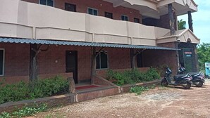 A two-story building with a flat roof, a balcony on the upper floor, and a covered entrance area. - Stone Wood Stay (Bhatkal)