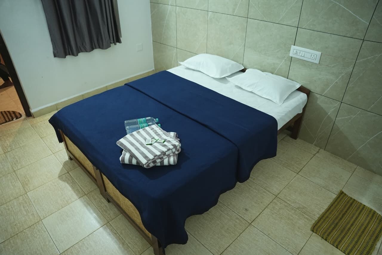 A room with a bed, a folded towel, and a bottle on the bed.