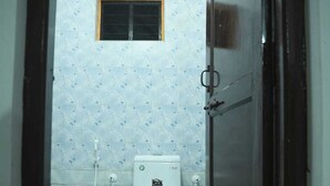 A bathroom with a toilet, a window, and a tiled floor. - Stone Wood Stay (Bhatkal)