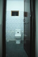 Un baño con inodoro, ventana y suelo de baldosas.