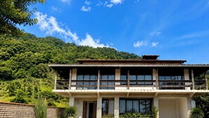 A two-story building with a balcony, surrounded by greenery and a mountainous backdrop. - SOLAR DO VALE VERDE (Corupá)