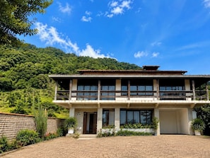 A two-story building with a balcony, surrounded by greenery and a mountainous backdrop. - SOLAR DO VALE VERDE (Corupá)