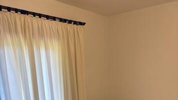 Un dormitorio con cama, cortinas blancas y cabecera de madera.