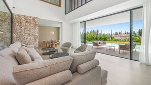 A modern living room with a sofa, a dining area, and a view of a swimming pool. - VILLA TROPHY BY VACATION MARBELLA (Marbella)