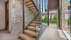 A modern staircase with glass railings leading to an upper level, surrounded by stone walls and a view of greenery. - VILLA TROPHY BY VACATION MARBELLA (Marbella)