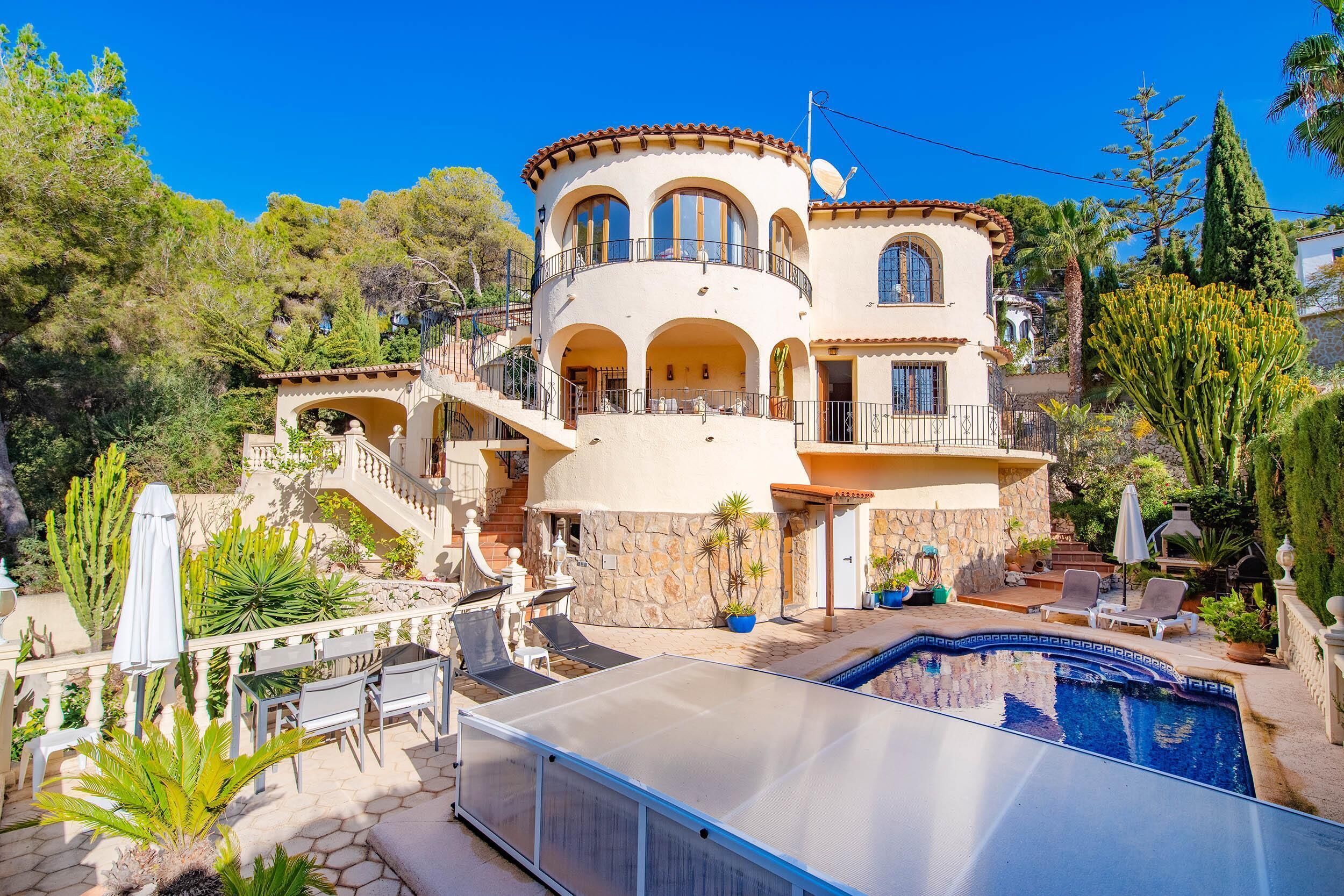 Une villa de style méditerranéen dotée d’une piscine, d’un espace salon extérieur et d’un escalier menant aux niveaux supérieurs.