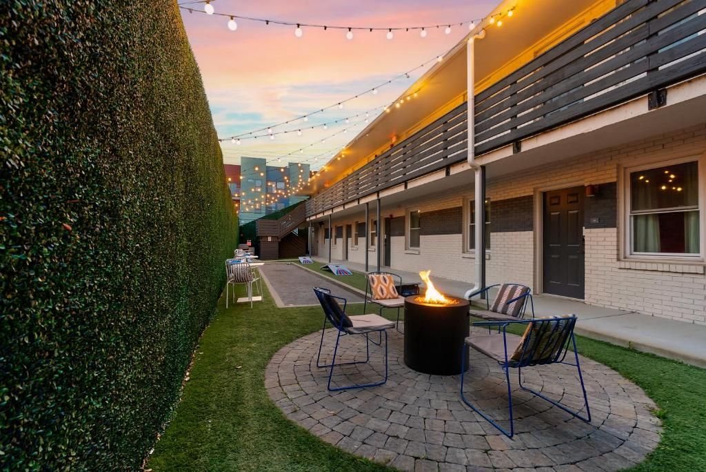 A courtyard with a fire pit, outdoor seating, and string lights.