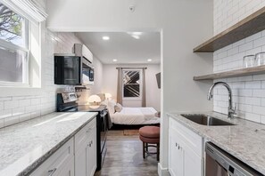 A compact kitchen with white cabinetry, a built-in oven, and a sink. - State Street (Nashville)