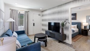 Una sala de estar moderna con un sofá, un televisor, una mesita y una cama.