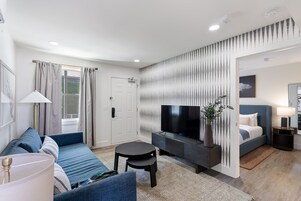Una sala de estar moderna con un sofá, un televisor, una mesita y una cama.