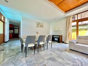 A dining area with a marble floor, a dining table with chairs, a sofa, and a fireplace. - The Midas Pool Villa (Banglamung)