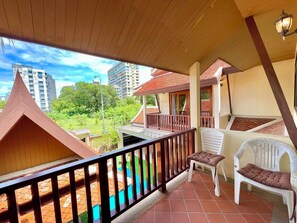 A balcony with a view of surrounding buildings, a tiled floor, and a railing. - The Midas Pool Villa (Banglamung)