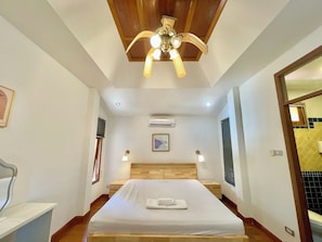 A hotel room with a wooden ceiling, a bed with a white bedspread, two bedside lamps, an air conditioning unit, and a framed picture on the wall. - The Midas Pool Villa (Banglamung)