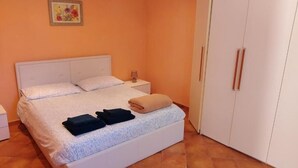A bedroom with a bed, nightstand, and wardrobe.