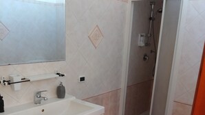 A bathroom with a white sink, mirror, and shower.