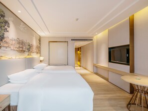 A hotel room with a large bed, a TV, a small table, and a painting on the wall. - Vienna International Hotel Huifuxi  (Guangzhou)