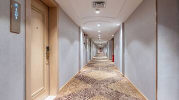 A hotel hallway with a patterned carpet, wooden doors, and a sign indicating room number 1501.