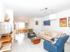 A modern living room with a sofa, armchairs, a coffee table, and a bookshelf. - Apartament Puig - Comarruga (Comarruga)
